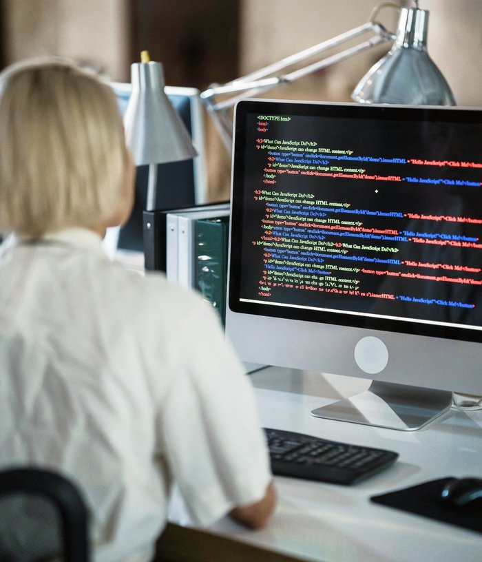 A web developer at work, the person is facing a computer screen which is filled with lines of code