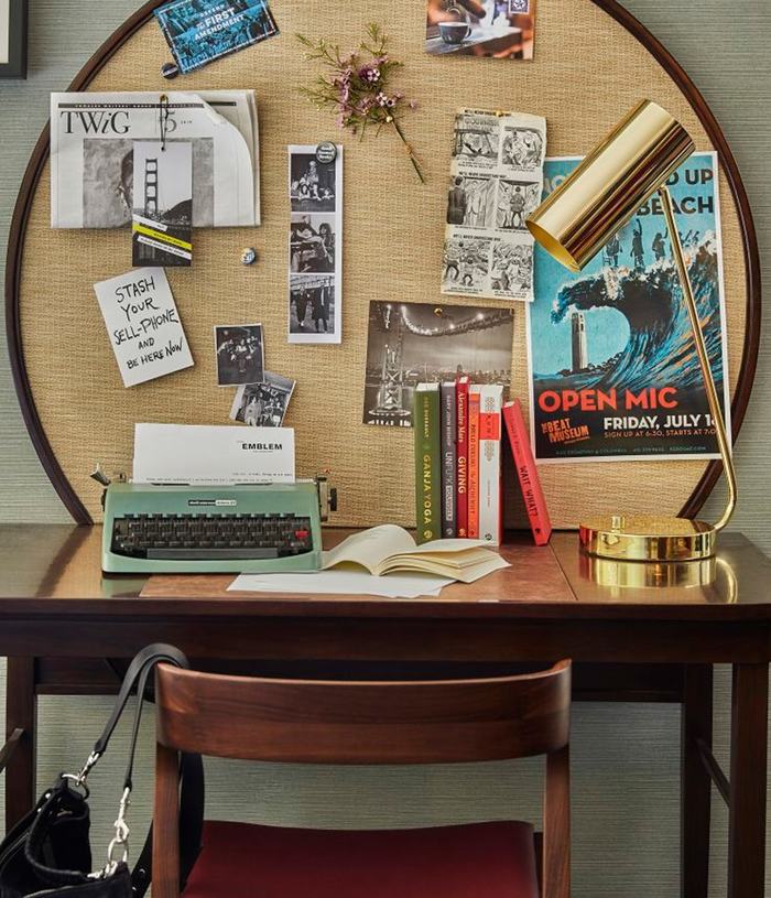 A desk in a Hotel Emblem room styled with various ephemera 