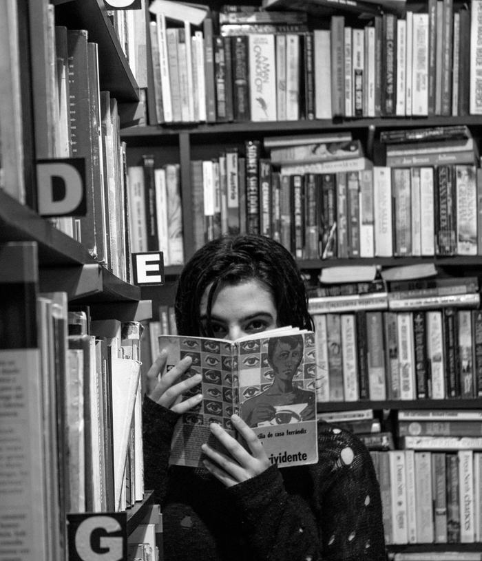 Black & white photography of a person lifting their gaze just above the pages of a book they were reading