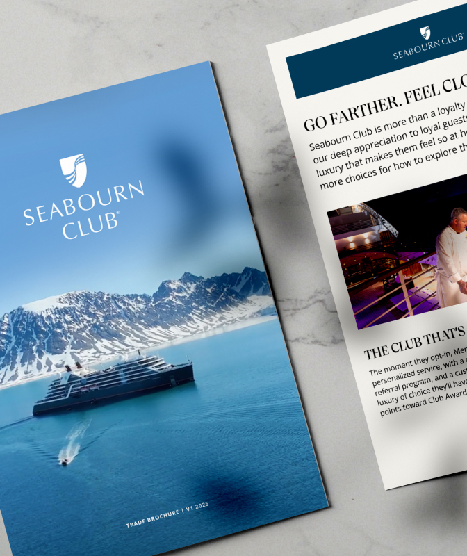 A Seabourn Club brochure on marble. The closed cover shows a cruise ship near snowy mountains. The open pages detail club benefits, featuring photos of a chef on deck and a scenic red bridge by a traditional building.