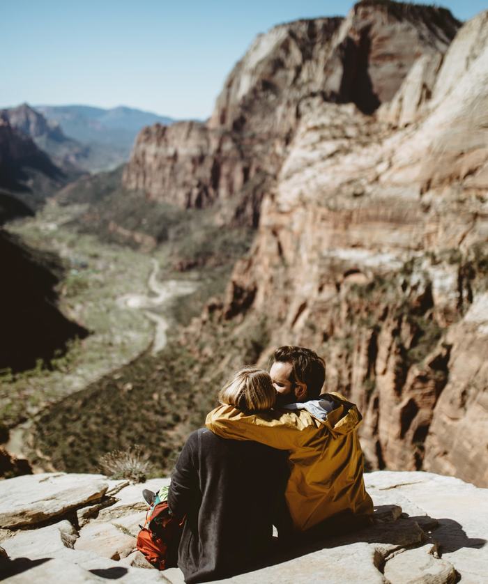 A heterosexual couple embrace while gazing out a beautiful valley view