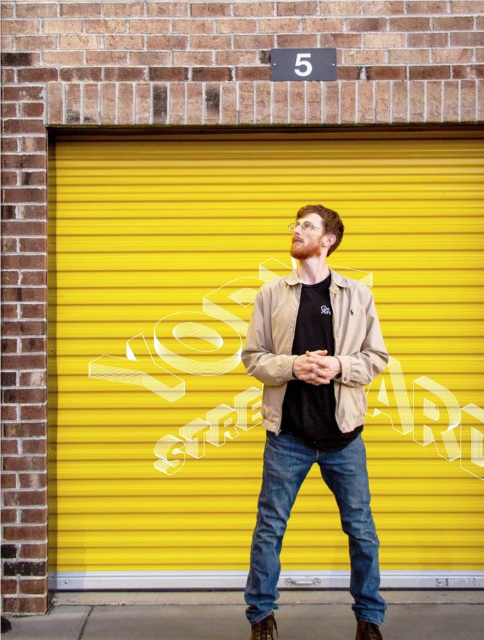 Bearded man standing in front of York Street Yards branded garage door