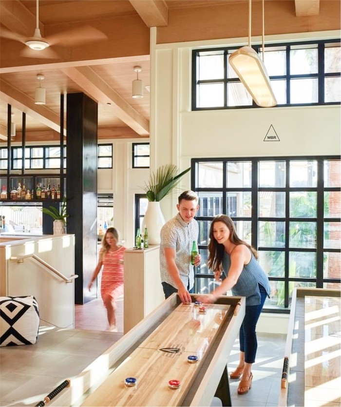 Interior of MBR with couple playing shuffleboard in light, bright common area